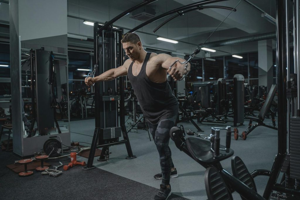 Muscular man working out in the gym using a cable crossover machine.