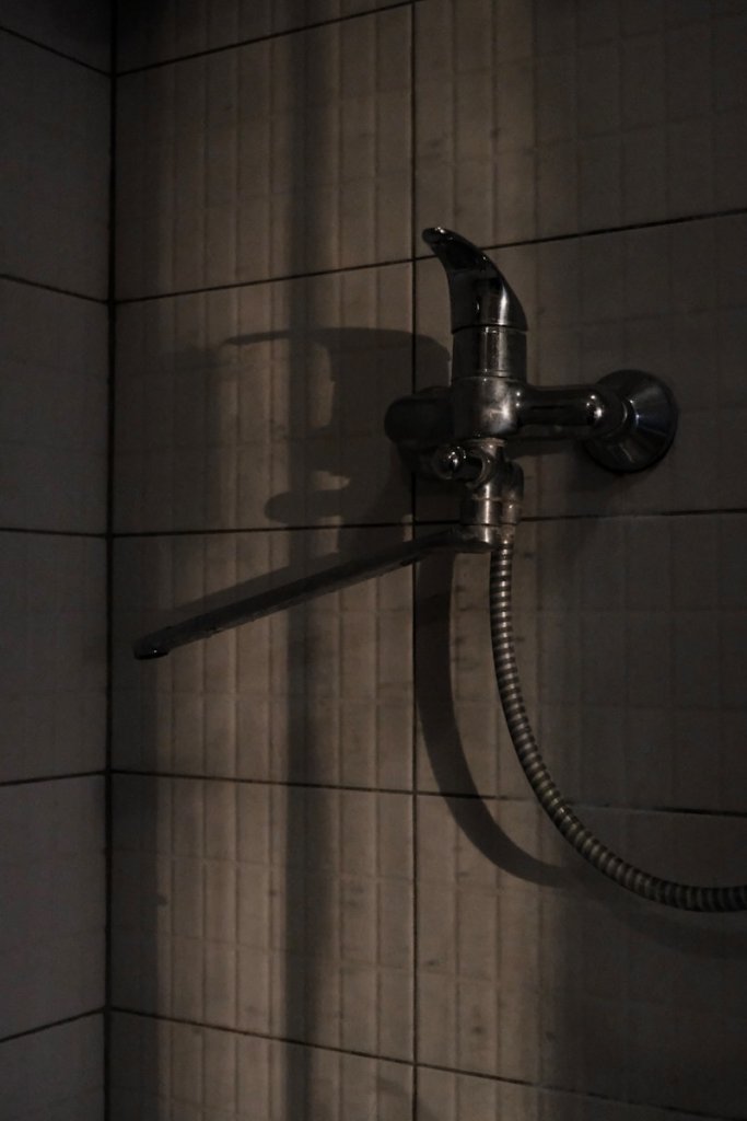 a faucet mounted to the side of a tiled wall