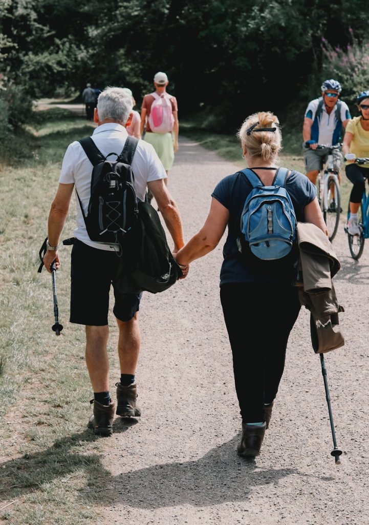Couple holds hands while walking down a path.