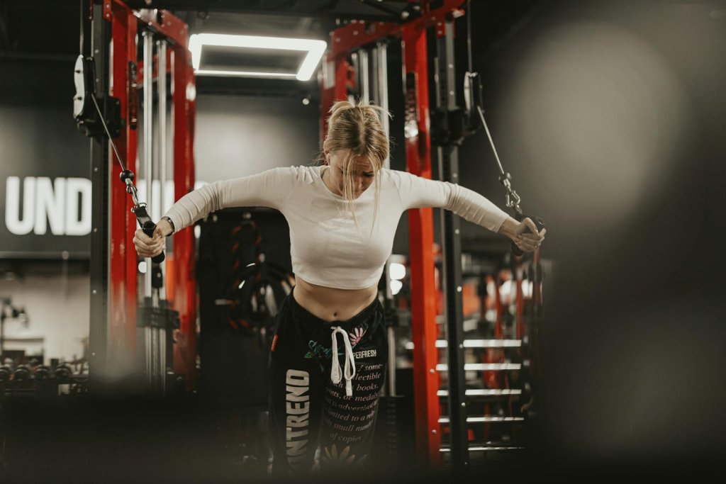 Focused young woman working out using a cable machine in a modern gym environment.