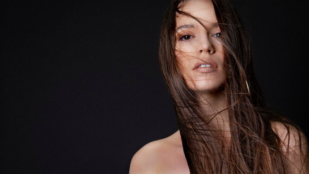 A woman poses with windblown hair.