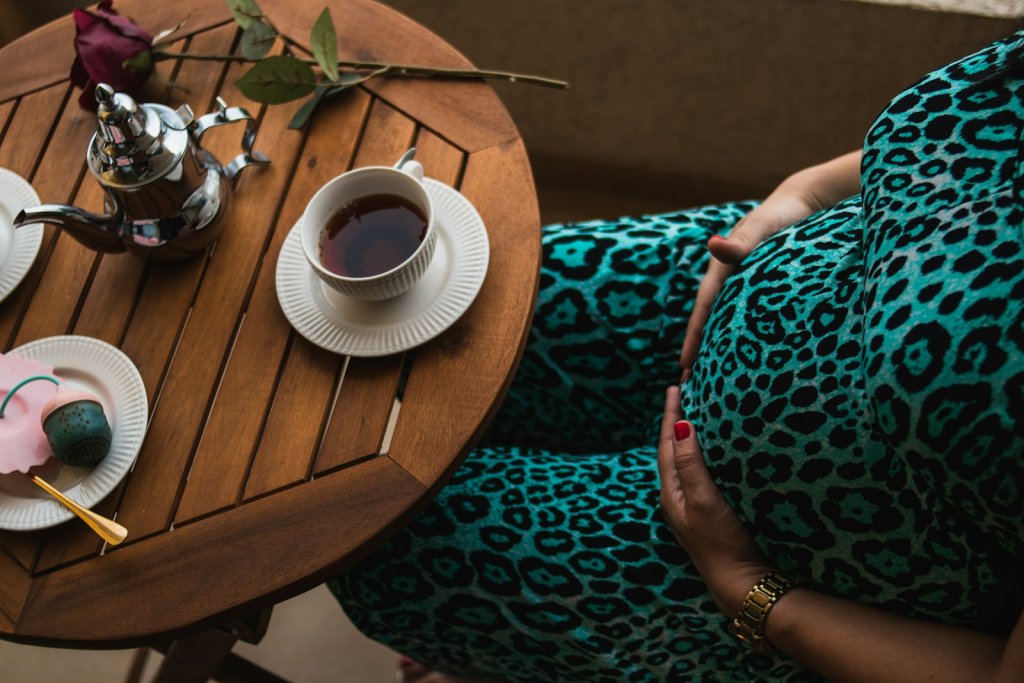 A pregnant woman sitting at a table with a cup of coffee