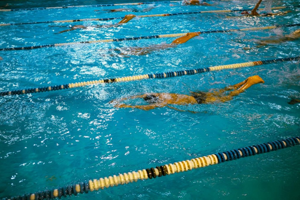 Indoor swimming competition with swimmers racing in lanes under artificial lighting.