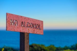 a rusted red sign sitting on top of a wooden pole