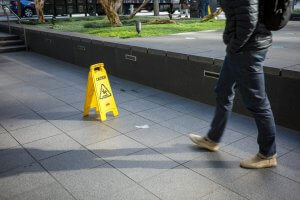 A man walking down a sidewalk next to a yellow caution sign